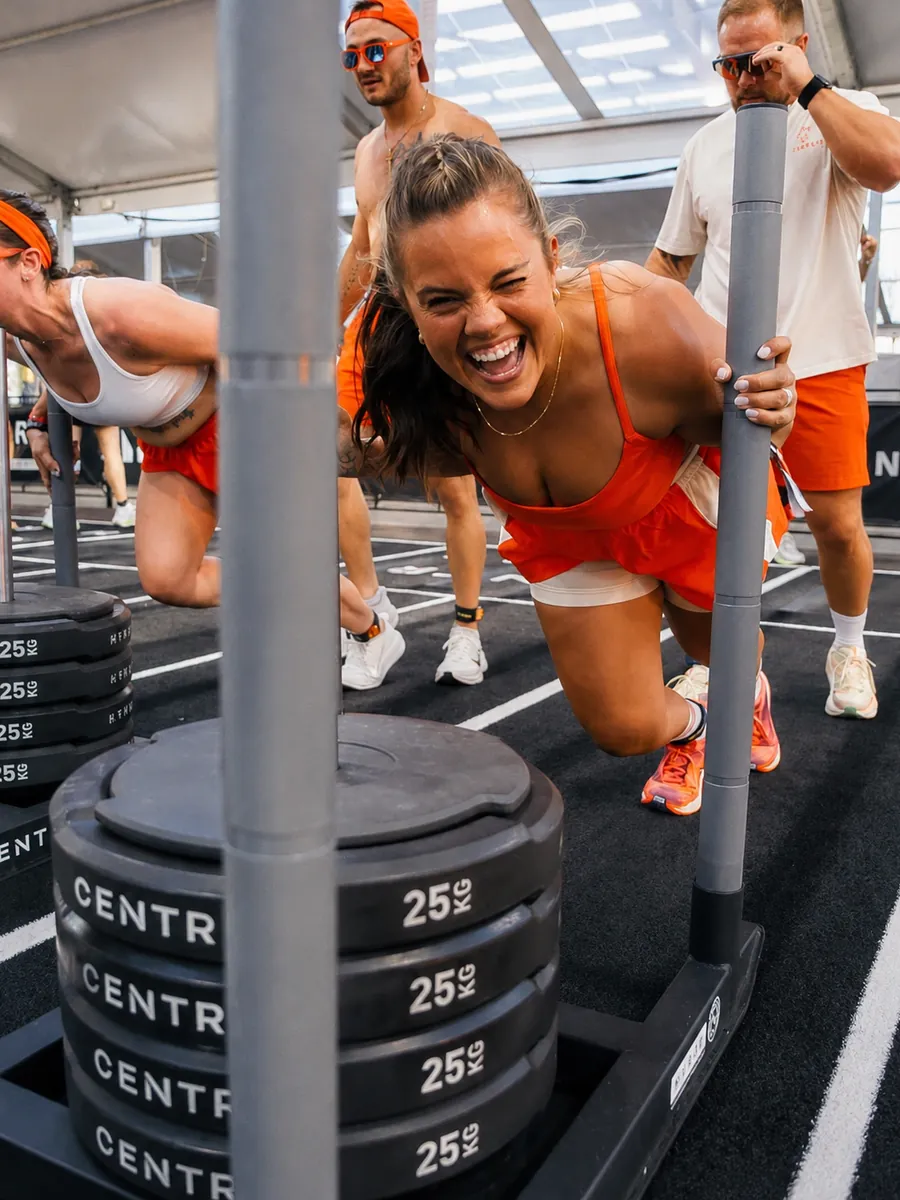 Athlete pushing a loaded sled during a Hyrox race workout